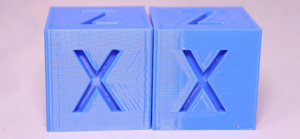 Two calibration cubes: left — with ghosting (fine horizontal lines after letter X), right — clean print