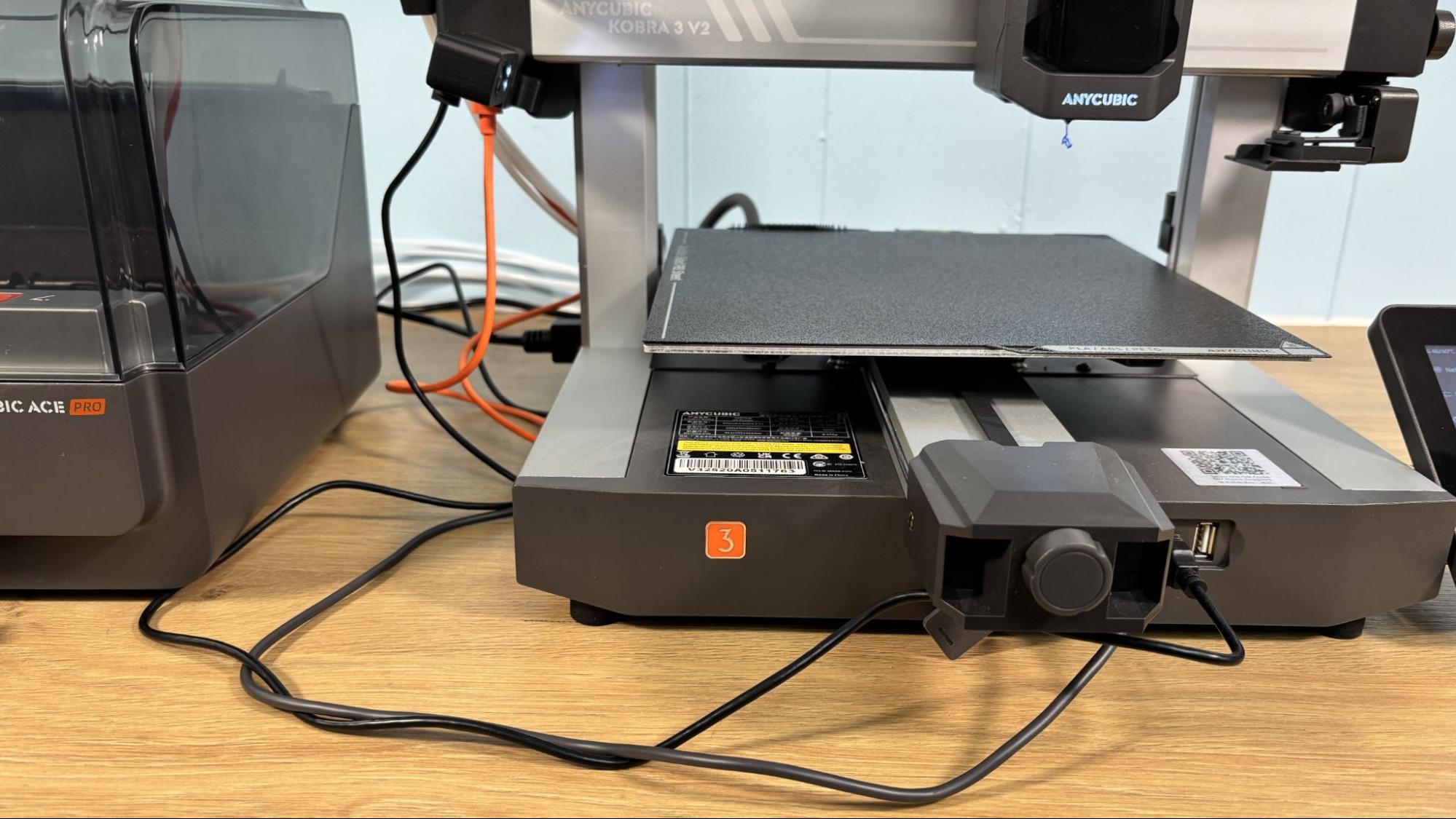 Anycubic Kobra 3 V2 рядом с блоком ACE Pro, видны передние USB-порты и разъём сигнального кабеля