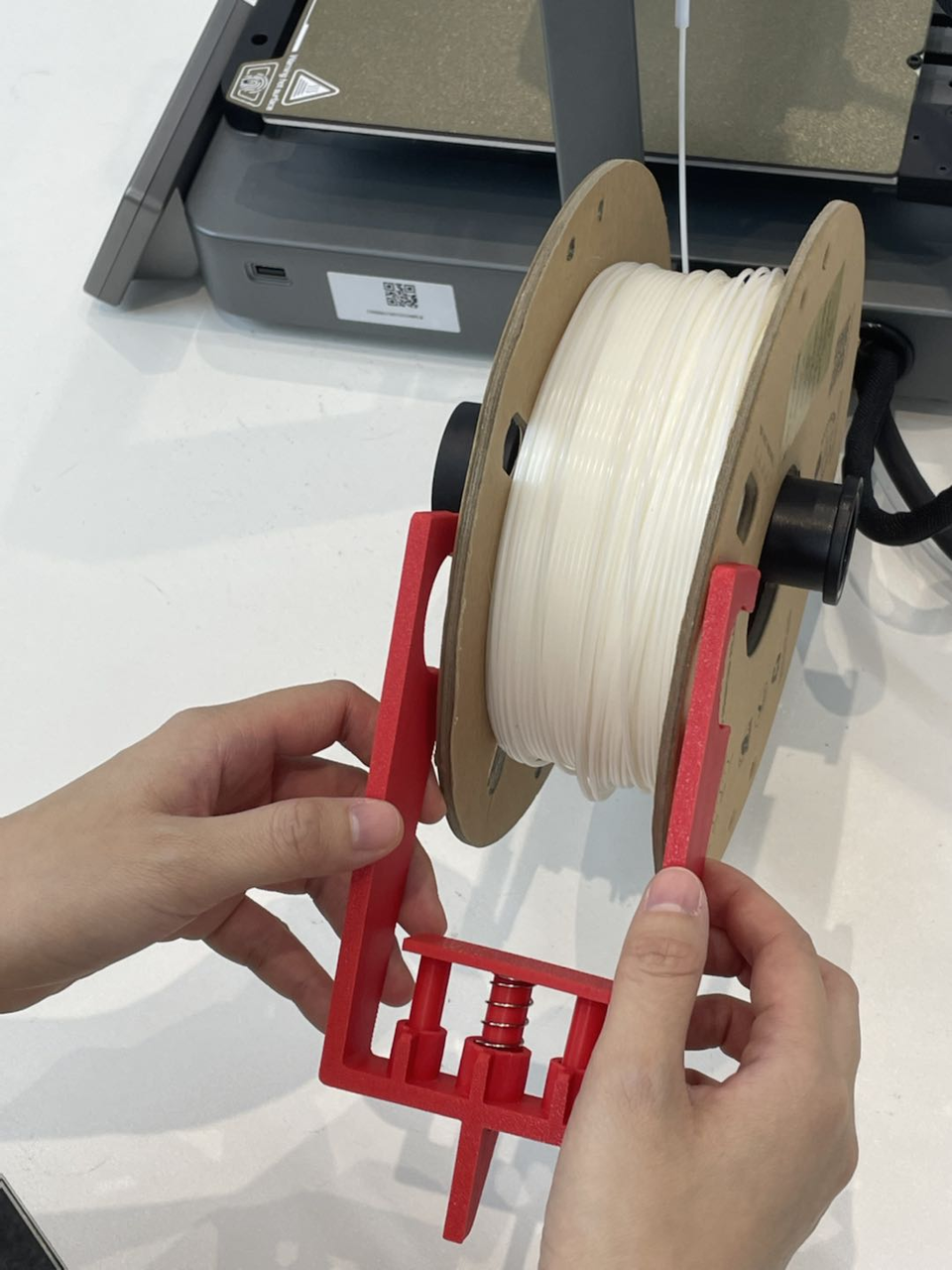 Anti-tangle bracket with its spring fitted to a filament spool