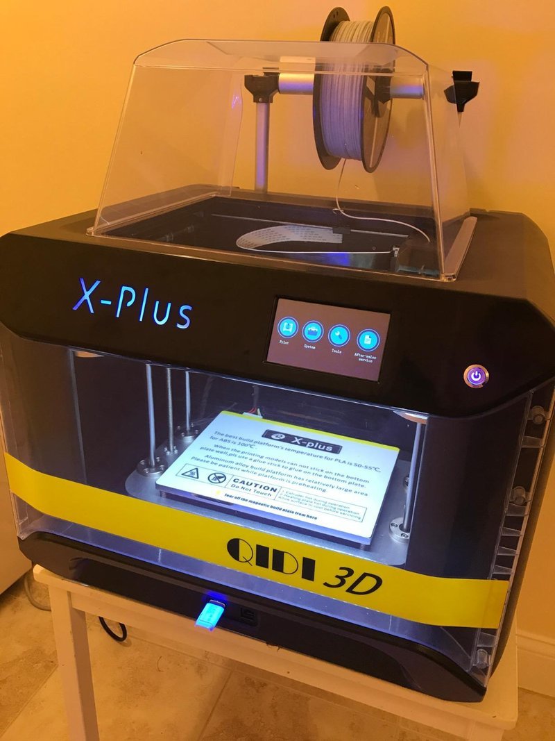 3D-принтер QIDI X-Plus у владельца: прозрачный верхний колпак, катушка сверху, сенсорный экран и предупреждающая наклейка о температуре стола