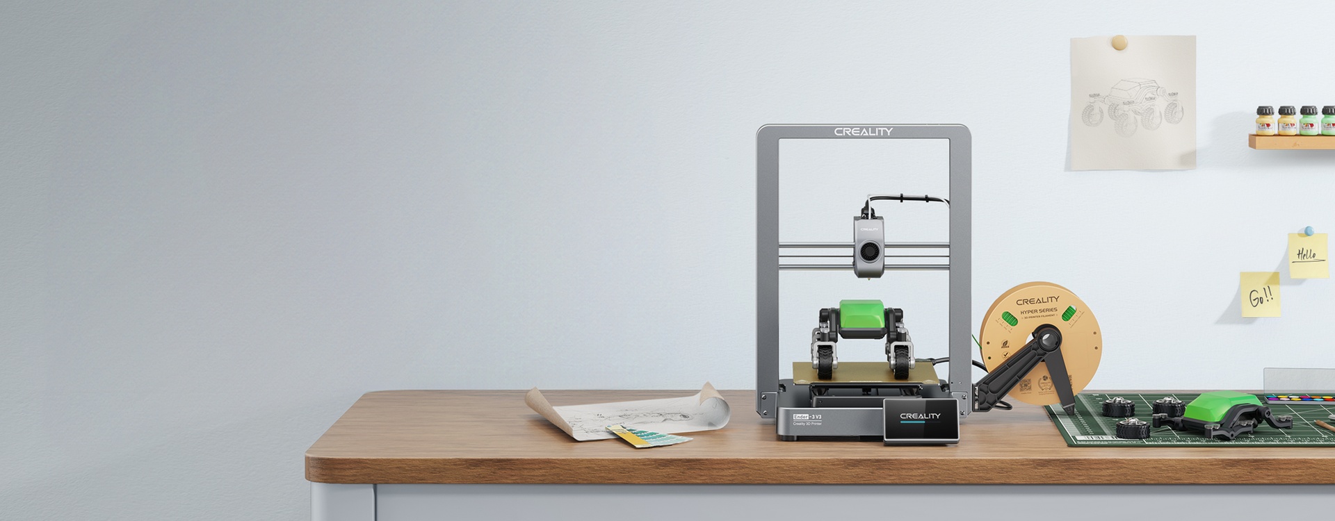 Creality Ender-3 V3 на рабочем столе с напечатанной зелёной моделью и катушкой Creality PLA