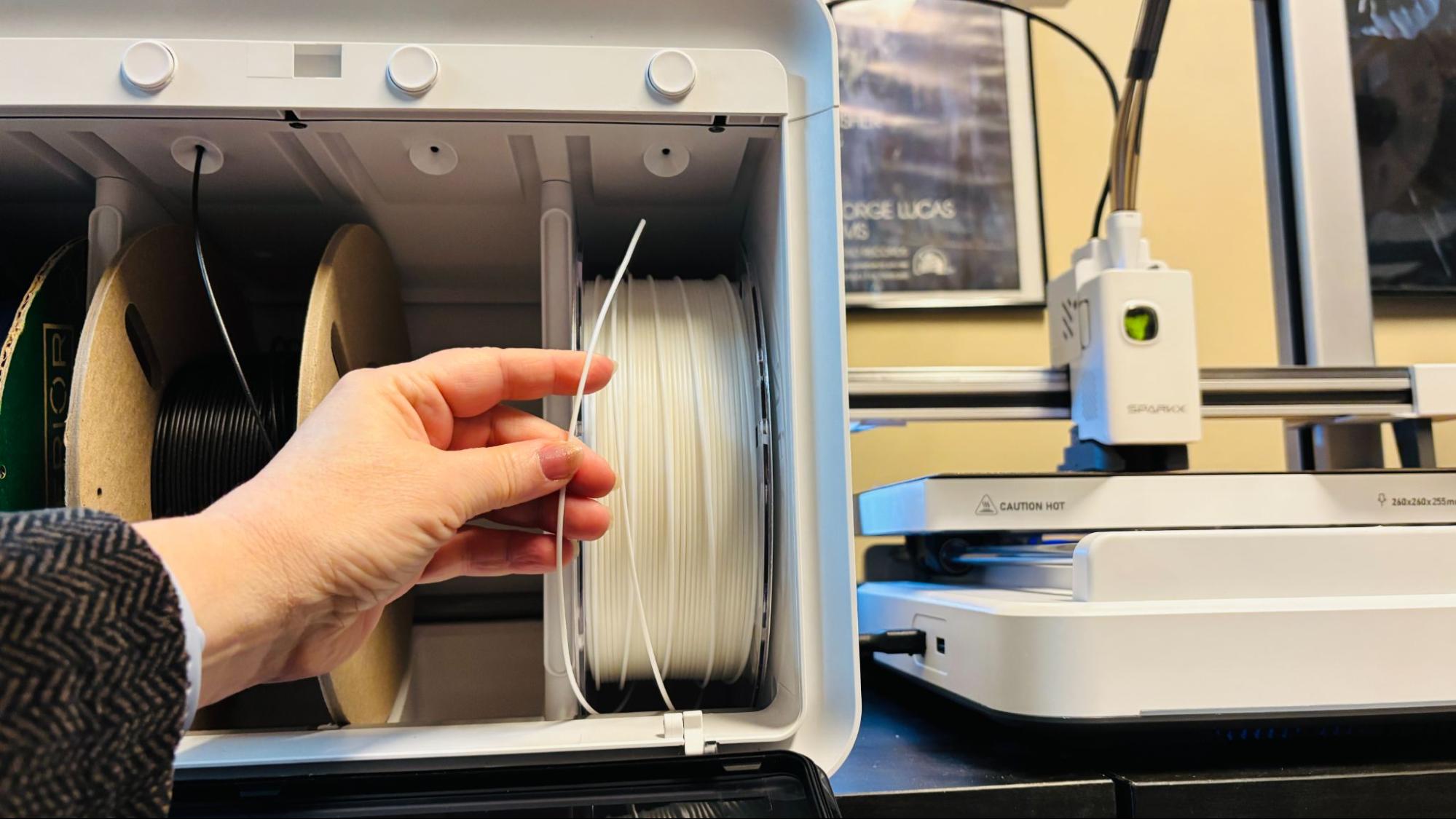Loading filament into CFS Lite — hand inserting white filament into the top port